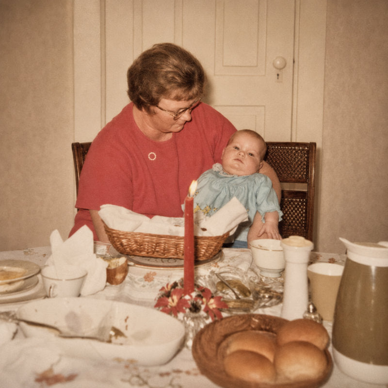 Woman and child at a dining table with bread and candles, vintage setting